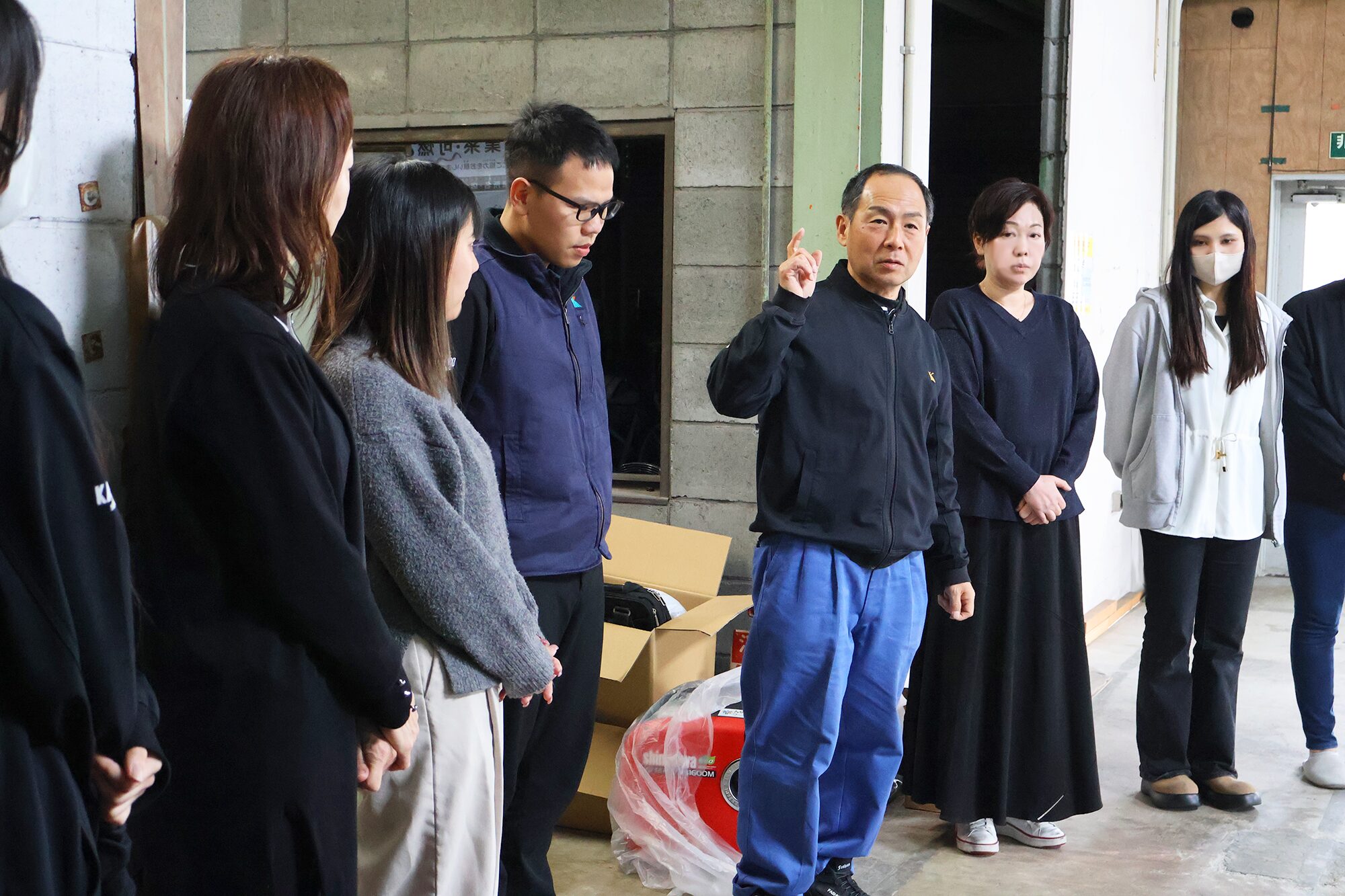 災害発生時の避難経路と避難場所を説明する安全グループと、説明を聞く弊社社員